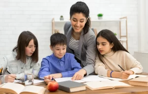 A teacher sitting with a student, helping her with a task