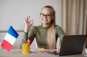 Young girl sitting at desks in a classroom, raising their hands to answer a question